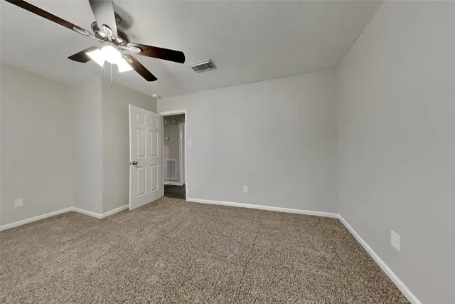 a view of an empty room and chandelier fan