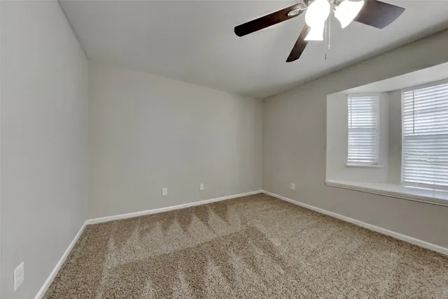 an empty room with a chandelier fan and windows