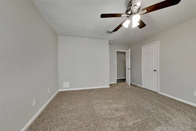 an empty room with a ceiling fan and carpet