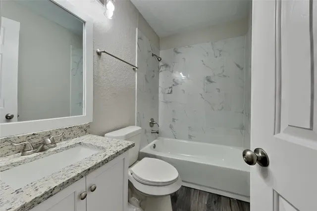 a bathroom with a granite countertop sink toilet and shower