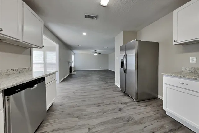 a view of a refrigerator in kitchen and wooden cabinets