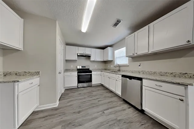 a kitchen with granite countertop white cabinets and white appliances