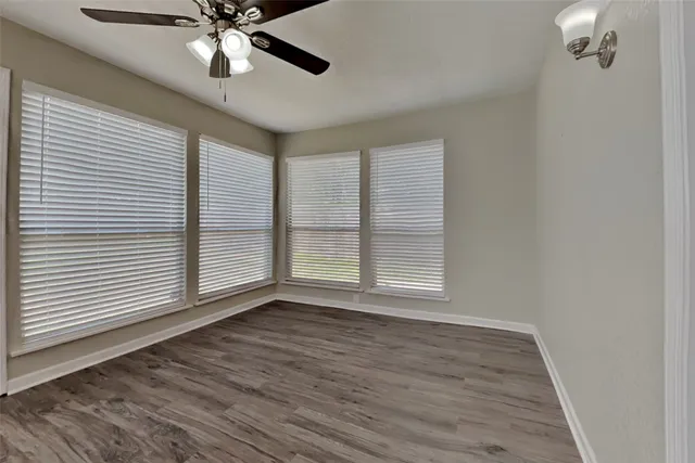 a view of an empty room with a window and wooden floor
