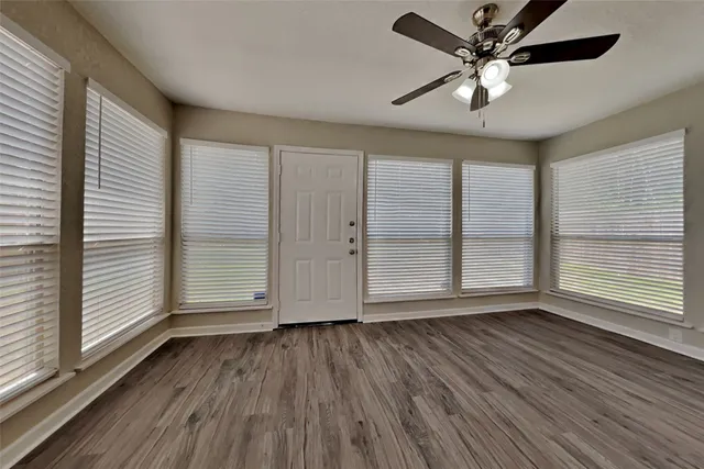 an empty room with wooden floor and windows