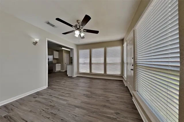 a view of an empty room with a window and wooden floor