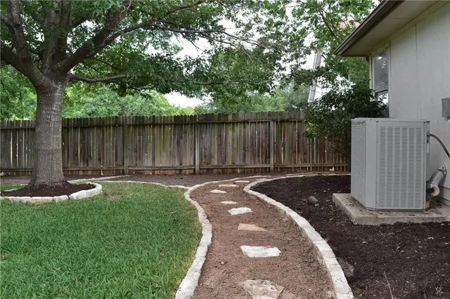 a view of a backyard with wooden fence and a large tree