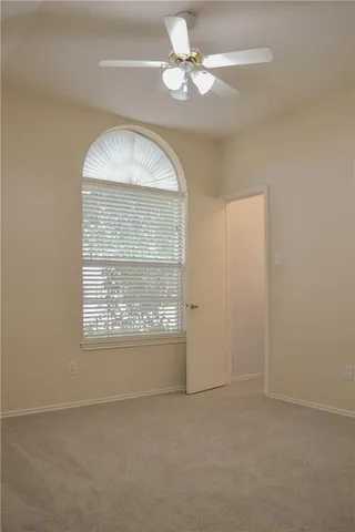an empty room with a chandelier fan and windows