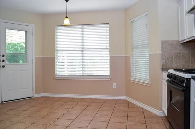 an empty room with chandelier fan and windows