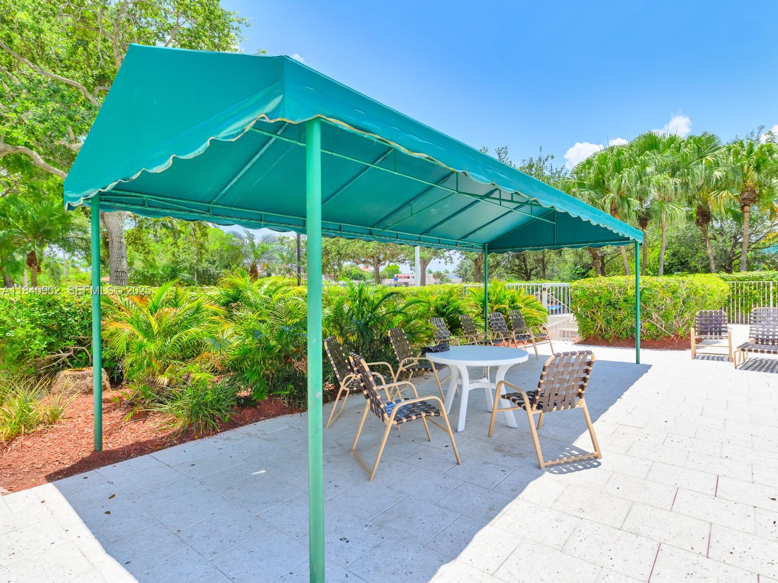 933 Falling Water Road Weston, FL 33326 - Photo 49 of 58 a patio with a patio table and chairs under an umbrella