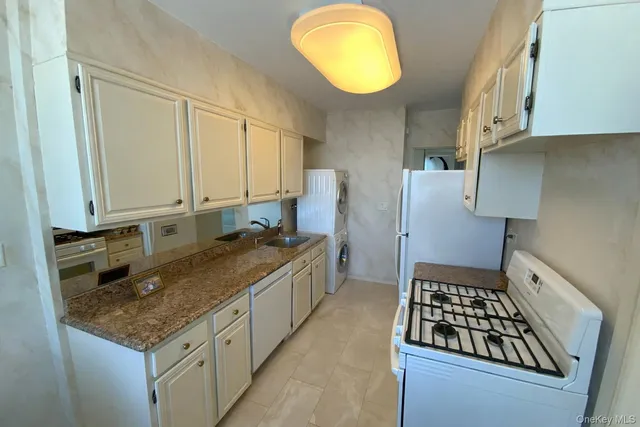a kitchen with granite countertop a sink a stove and a wooden cabinets