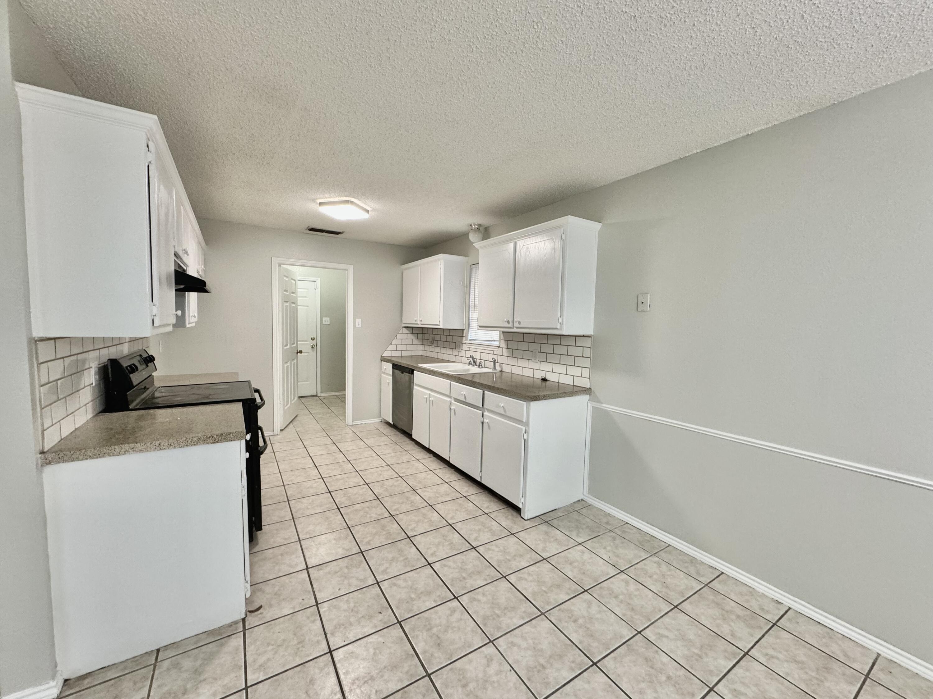 1003 Juneau Avenue Lubbock, TX 79416 - Photo 7 of 21 a kitchen with a sink a stove cabinets and a counter top space