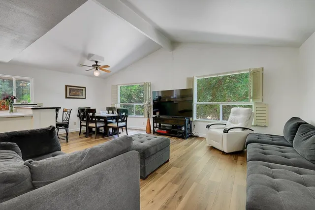 a living room with stainless steel appliances furniture and a flat screen tv