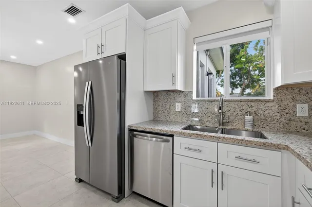 a kitchen with stainless steel appliances white cabinets and a window