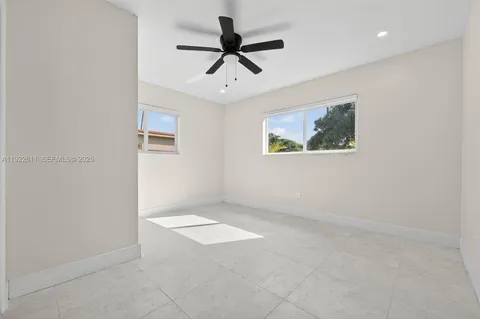 an empty room with windows and ceiling fan