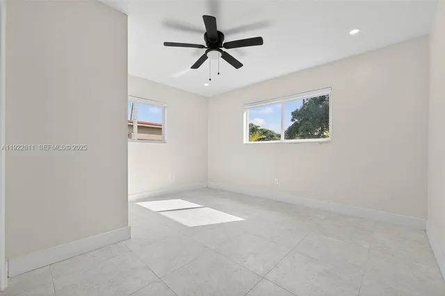 an empty room with windows and ceiling fan