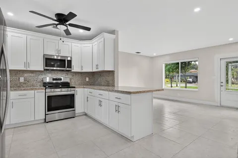 a kitchen with granite countertop a stove a microwave and a refrigerator