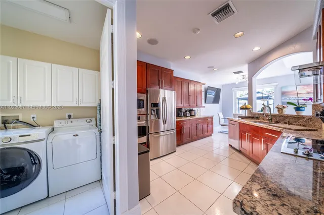 a kitchen with stainless steel appliances kitchen island granite countertop a refrigerator and a stove top oven