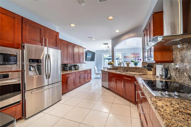 a large kitchen with stainless steel appliances granite countertop a stove refrigerator a sink and dishwasher