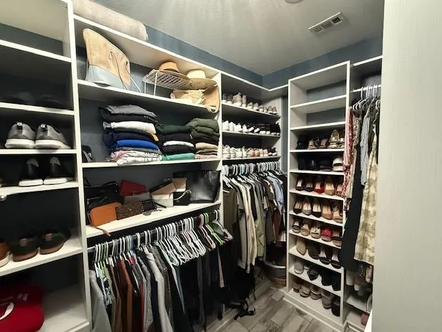 a view of walk in closet with clothes and shoes