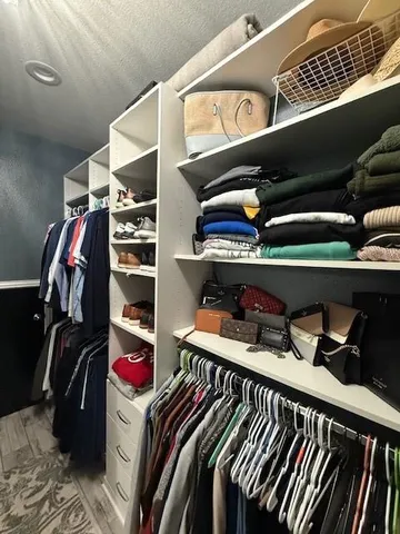 a view of walk in closet with clothes and shoes