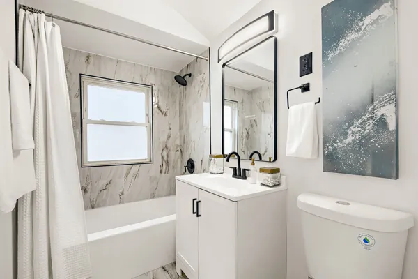 a bathroom with a sink a toilet a mirror a bathtub and shower