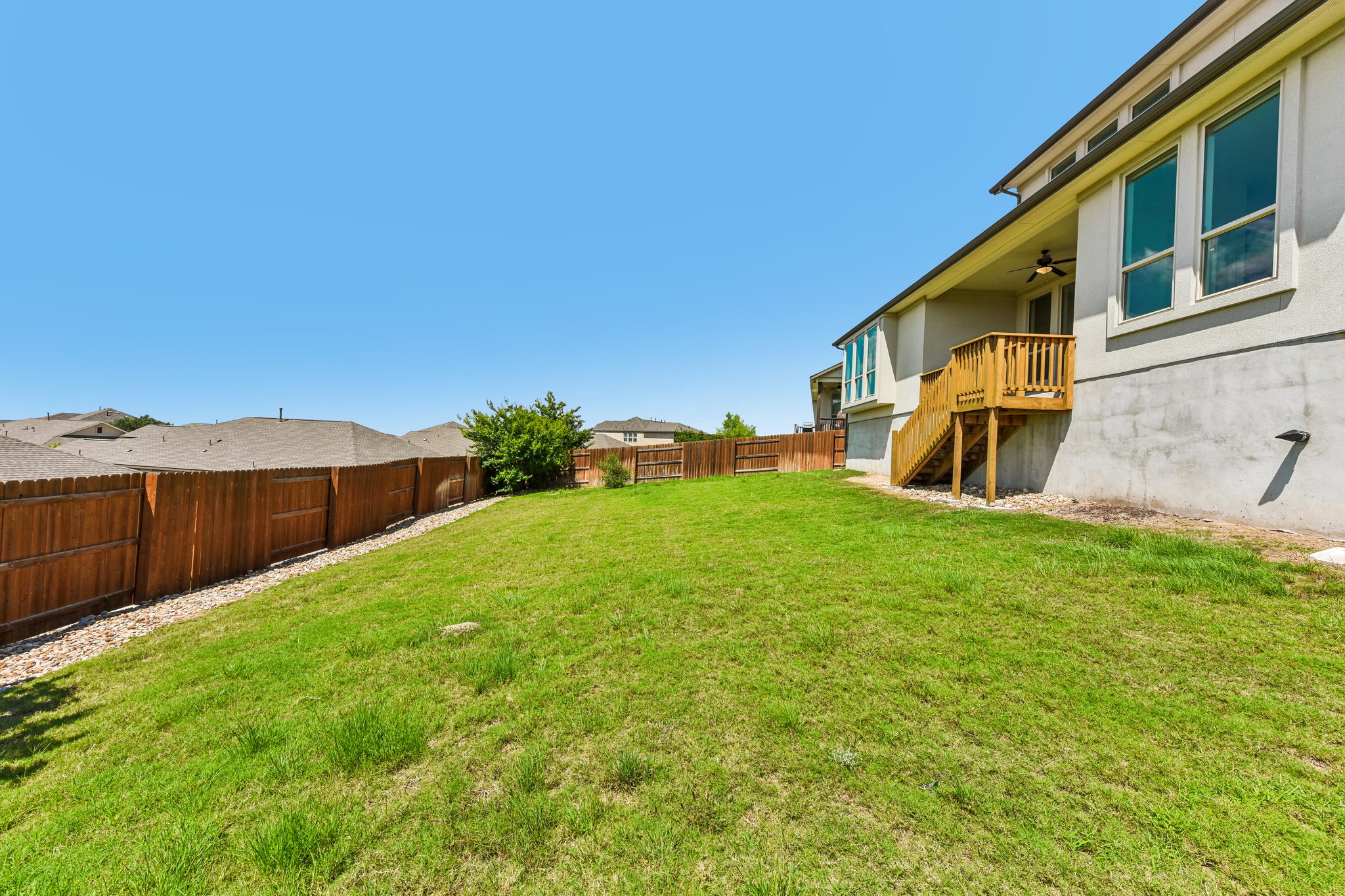 19113 Freeman Circle Austin, TX 78738 - Photo 26 of 37 A spacious backyard with vibrant green grass, secured by a sturdy wooden fence.