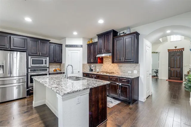 a kitchen with stainless steel appliances granite countertop a sink stove and refrigerator