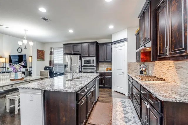 a kitchen with stainless steel appliances granite countertop a sink stove and refrigerator