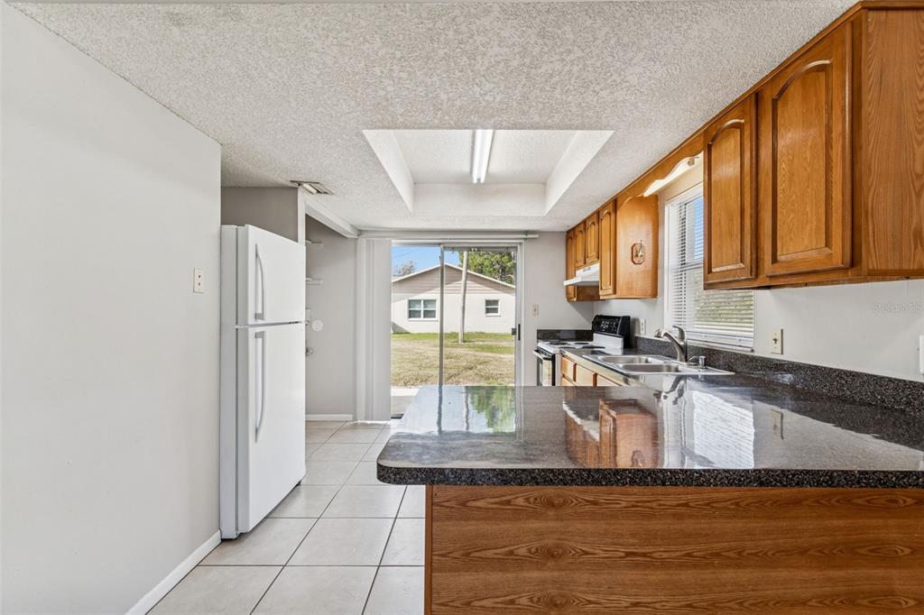 6024 Norton Road Lakeland, FL 33809 - Photo 21 of 56 a kitchen with kitchen island granite countertop a stove a sink and a refrigerator with wooden floor
