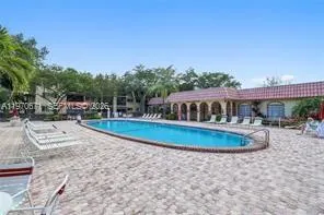 a view of a swimming pool with lawn chairs under an umbrella