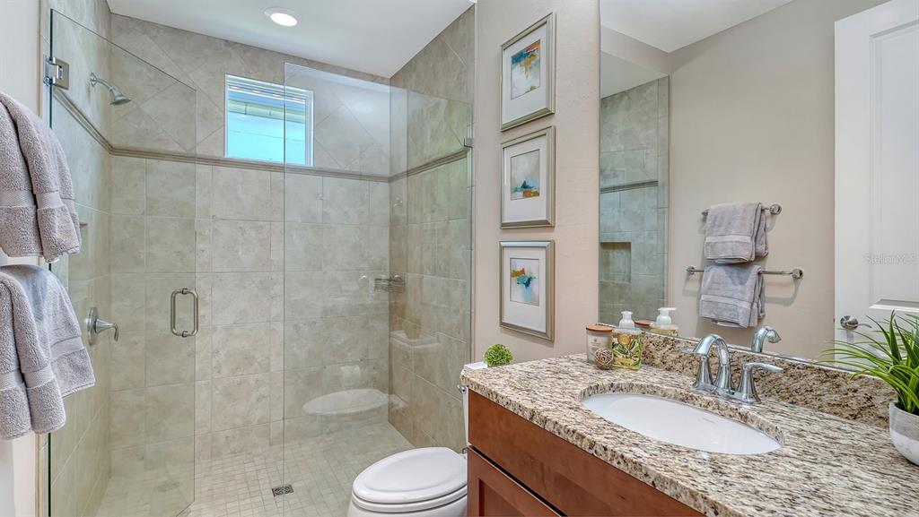 7975 Matera Court Lakewood Ranch, FL 34202 - Photo 40 of 83 a bathroom with a granite countertop sink toilet mirror and shower