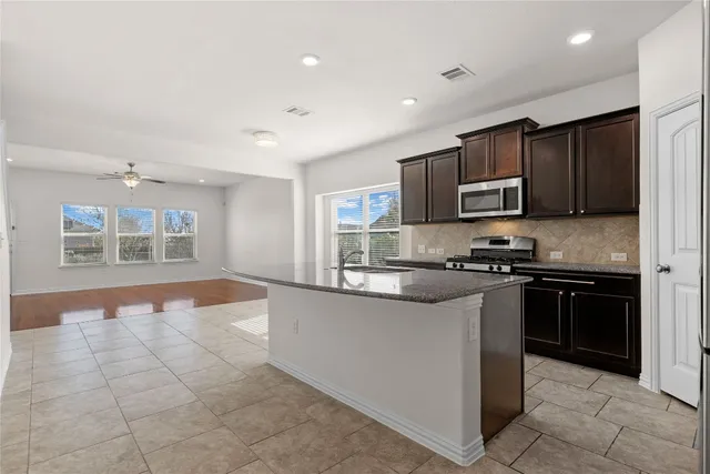 a kitchen with stainless steel appliances granite countertop a stove top oven a sink a counter top space and cabinets