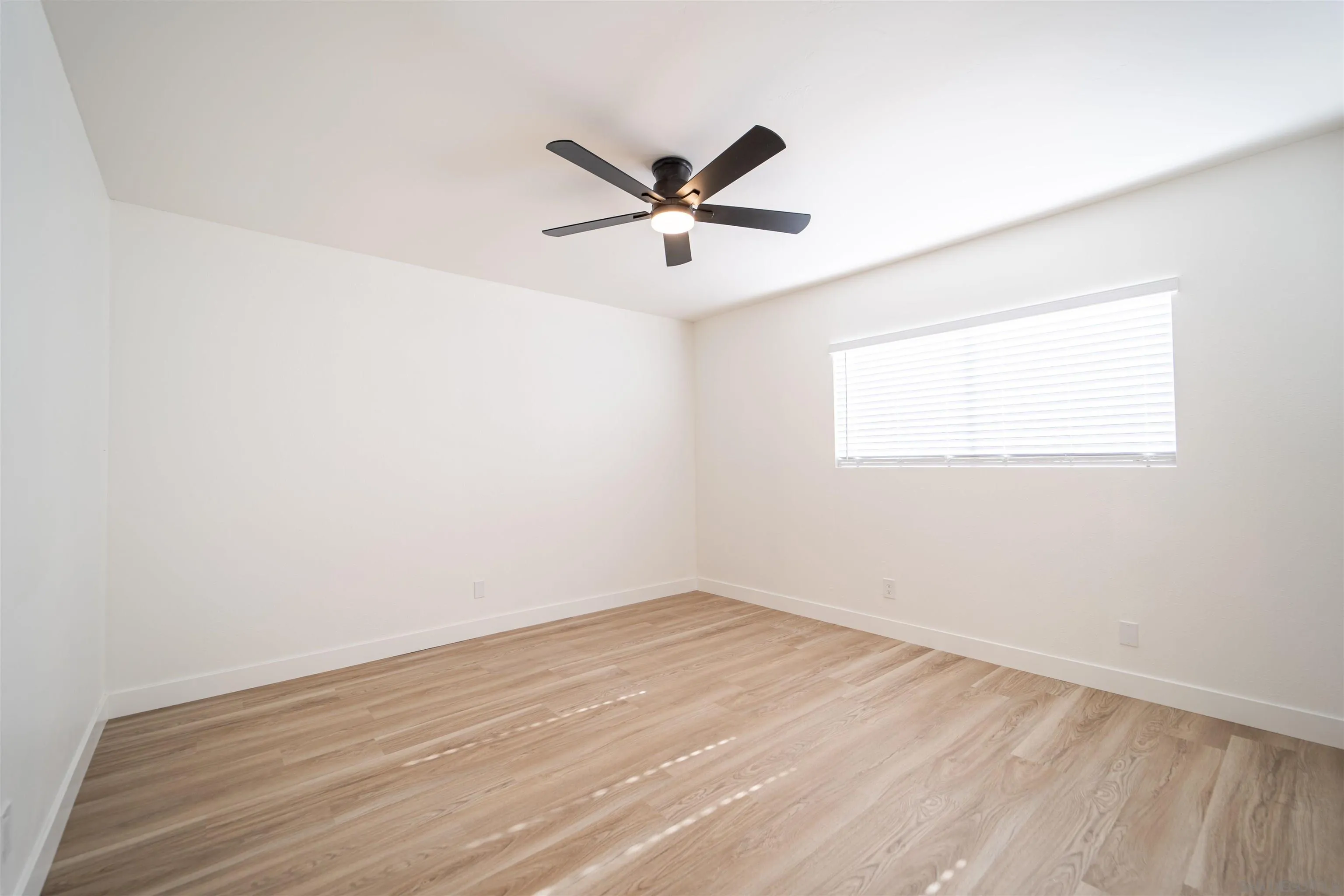 1306 West San Ysidro Boulevard, Unit D San Diego, CA 92173 - Photo 14 of 22 an empty room with wooden floor a ceiling fan and windows