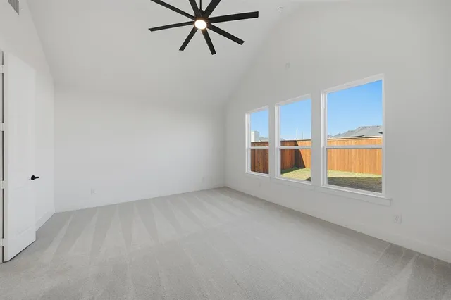 an empty room with chandelier fan and windows