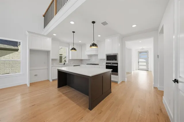 a large white kitchen with wooden floors and stainless steel appliances