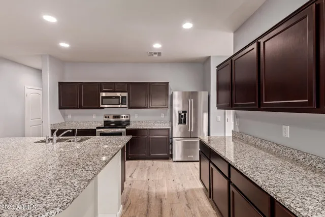 a kitchen with stainless steel appliances granite countertop a sink stove microwave and refrigerator