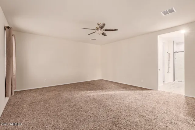 an empty room with chandelier fan and windows