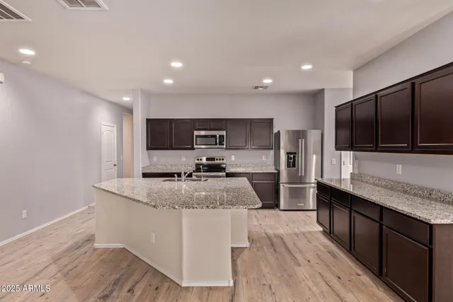 a large kitchen with stainless steel appliances kitchen island granite countertop a large counter top and wooden floors
