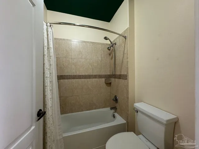 en empty room with a chandelier fan and a bathroom