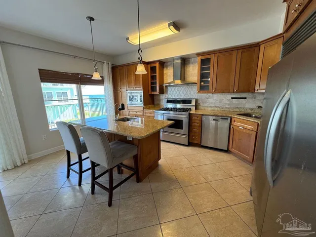 a kitchen with stainless steel appliances granite countertop a stove a sink a oven a dining table and chairs