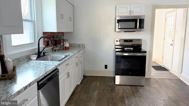 a kitchen with stainless steel appliances granite countertop a stove a sink and a microwave