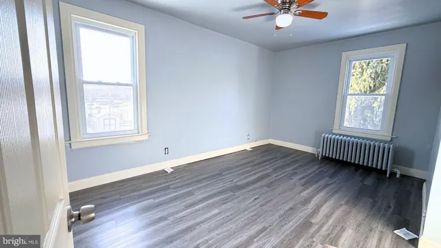 a view of empty room with wooden floor and fan