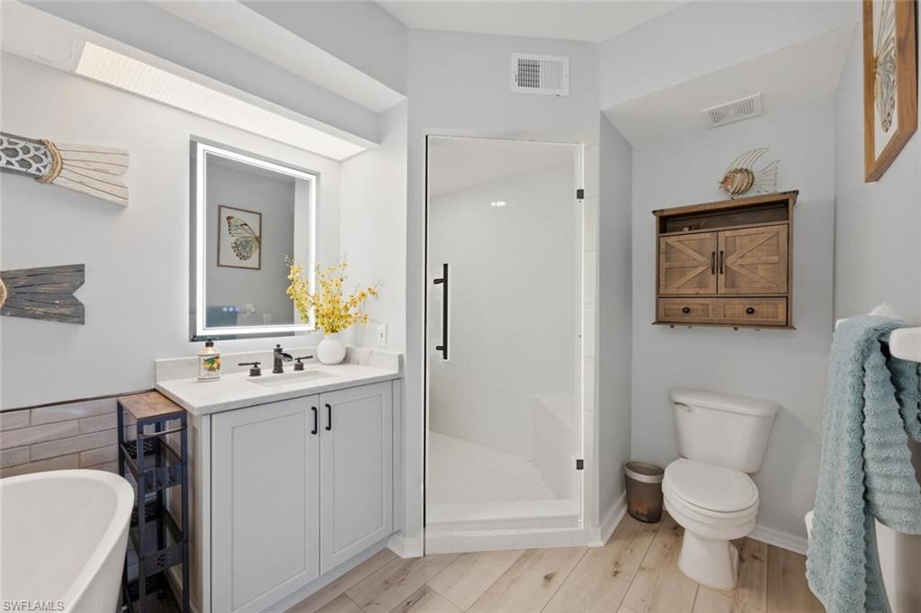 6899 Rain Lily Road, Unit 103 Naples, FL 34109 - Photo 19 of 39 Full bathroom with a soaking tub, a shower stall, vanity, and light wood-style floors