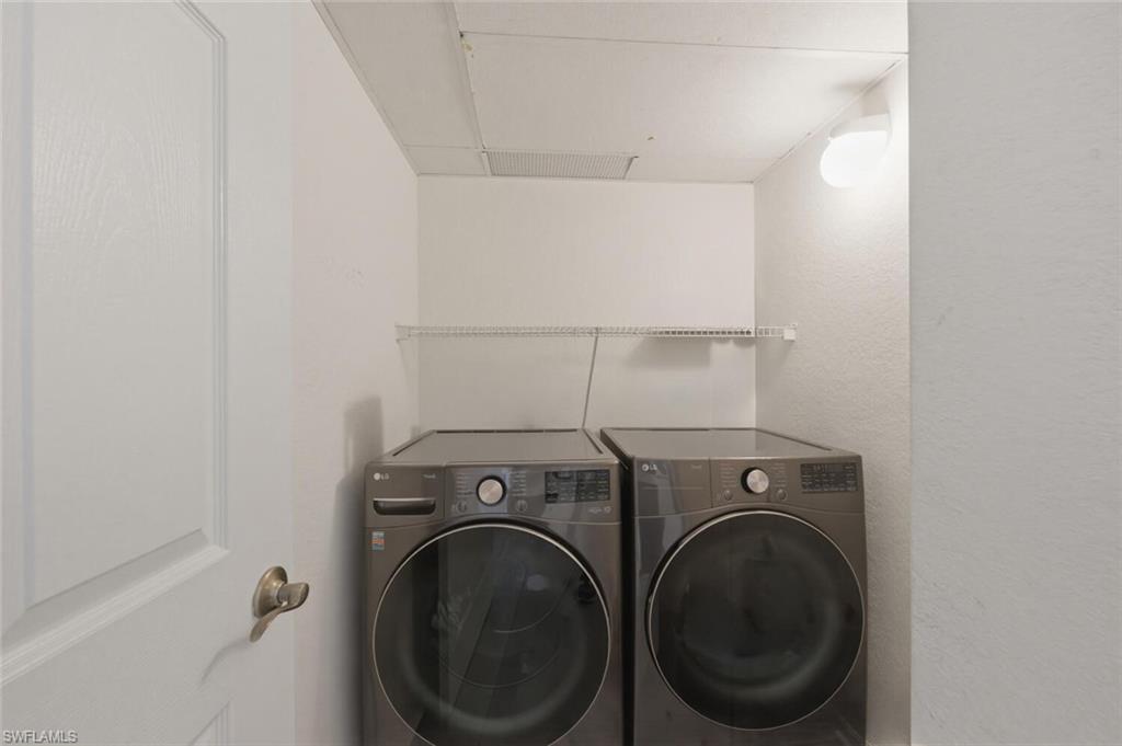 6899 Rain Lily Road, Unit 103 Naples, FL 34109 - Photo 24 of 39 Laundry room featuring washer and clothes dryer and a textured wall