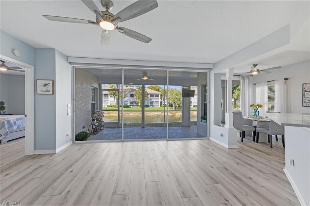 6899 Rain Lily Road, Unit 103 Naples, FL 34109 - Photo 8 of 39 Unfurnished living room featuring ceiling fan, light wood-style floors, and a water view