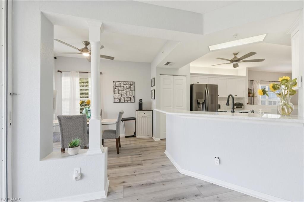 6899 Rain Lily Road, Unit 103 Naples, FL 34109 - Photo 10 of 39 Kitchen featuring a ceiling fan, white cabinetry, stainless steel fridge, and light wood-style floors