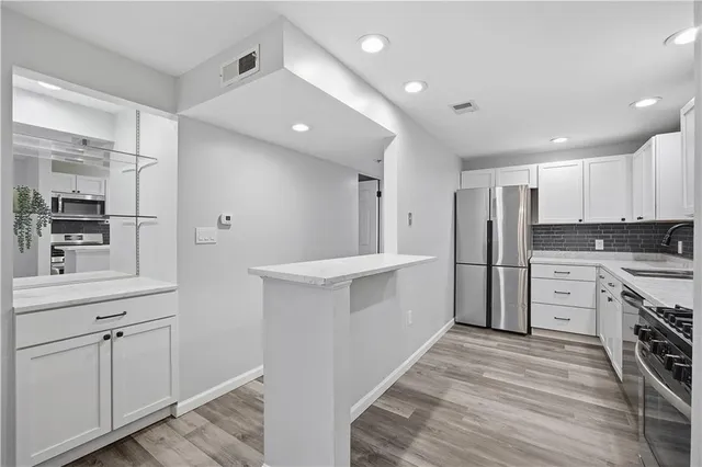 a kitchen with white cabinets and stainless steel appliances