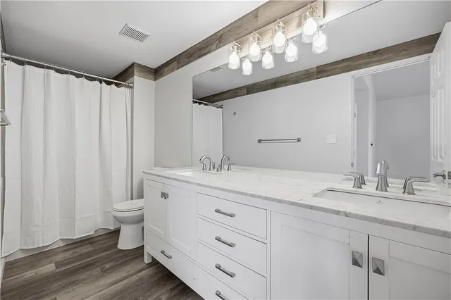 a bathroom with a granite countertop sink a toilet and a mirror