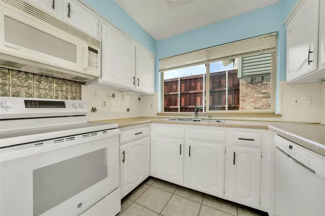 a kitchen with white cabinets and sink