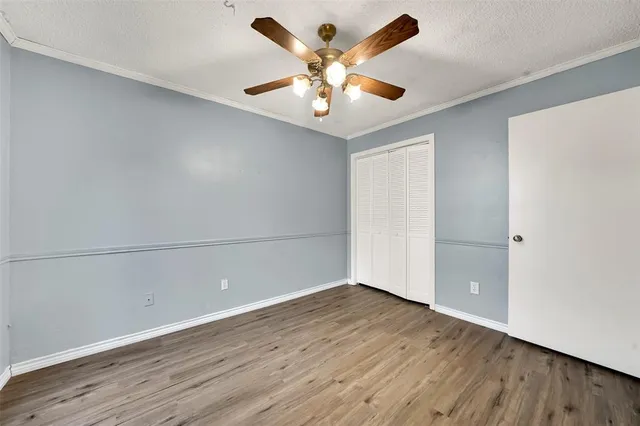 an empty room with wooden floor and ceiling fan